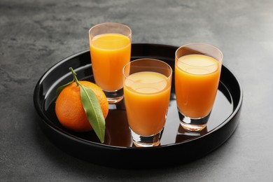 Photo of Delicious tangerine liqueur and fresh fruit on grey table