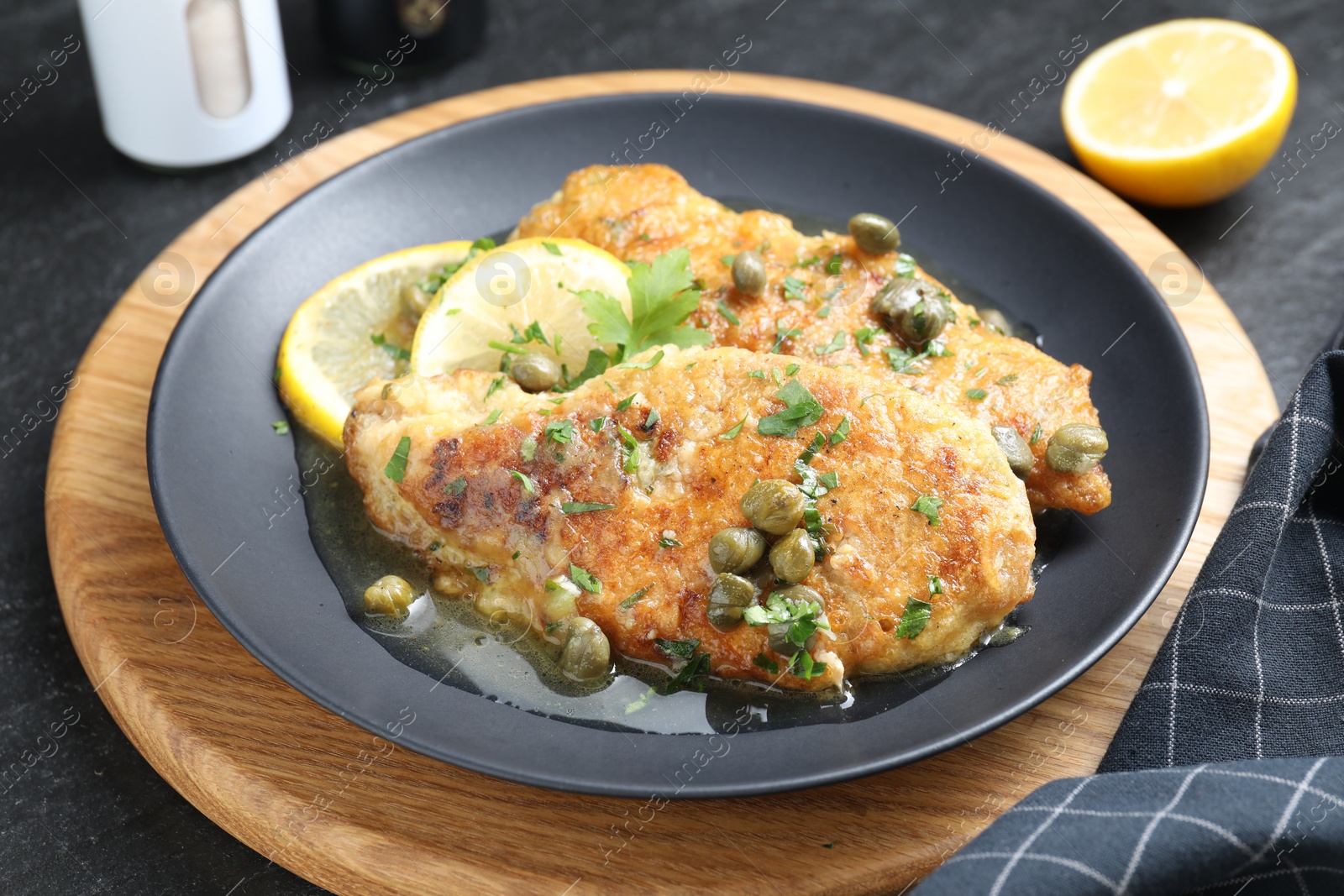 Photo of Delicious chicken piccata served on black table