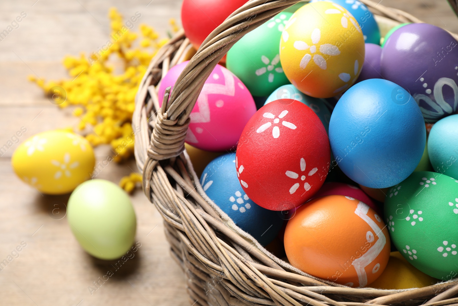 Photo of Basket with colorful Easter eggs on table, closeup
