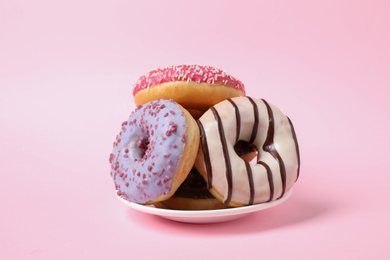 Photo of Tasty glazed donuts on pink background. Dessert food