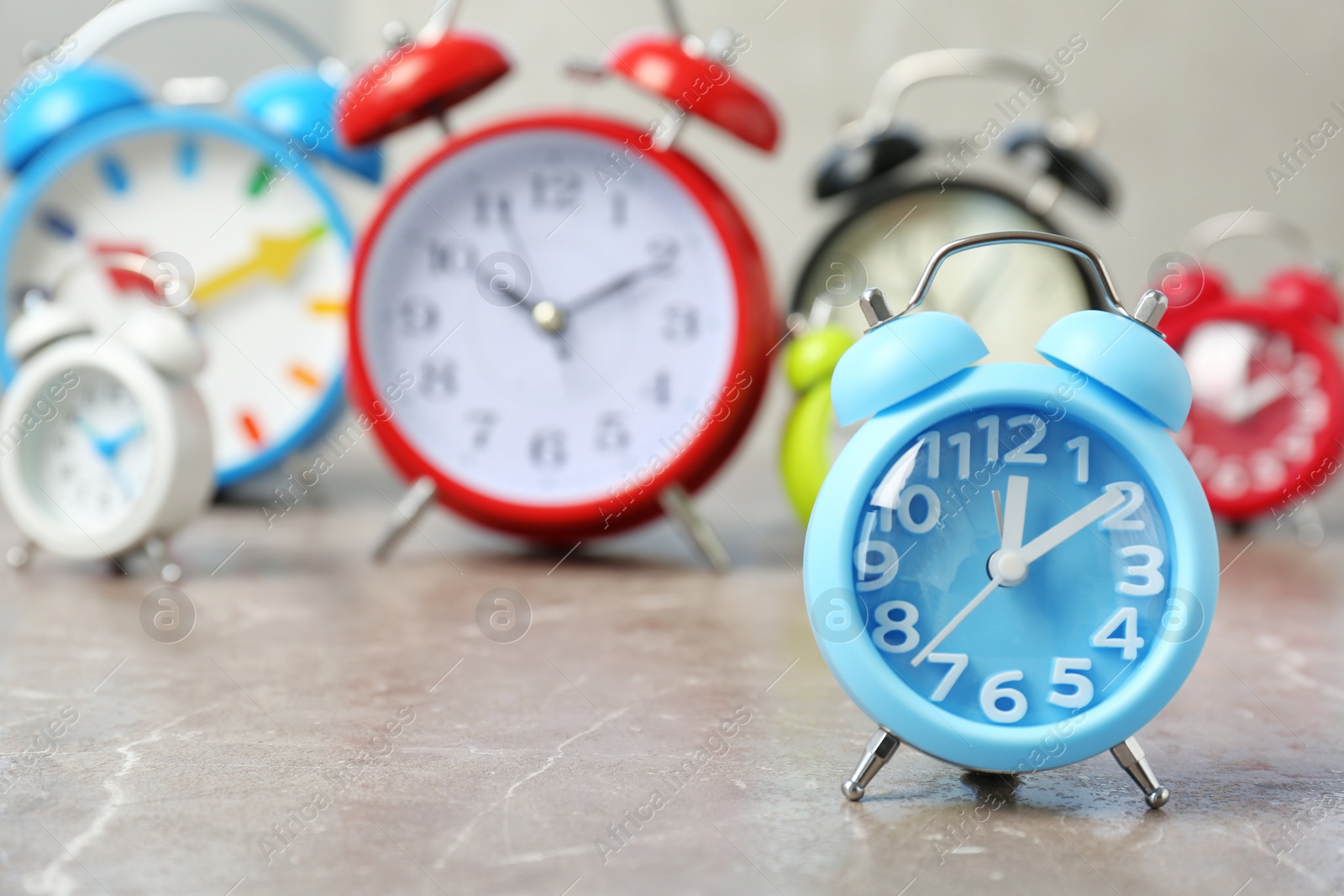 Photo of Blue alarm clock and many others on table. Time change concept