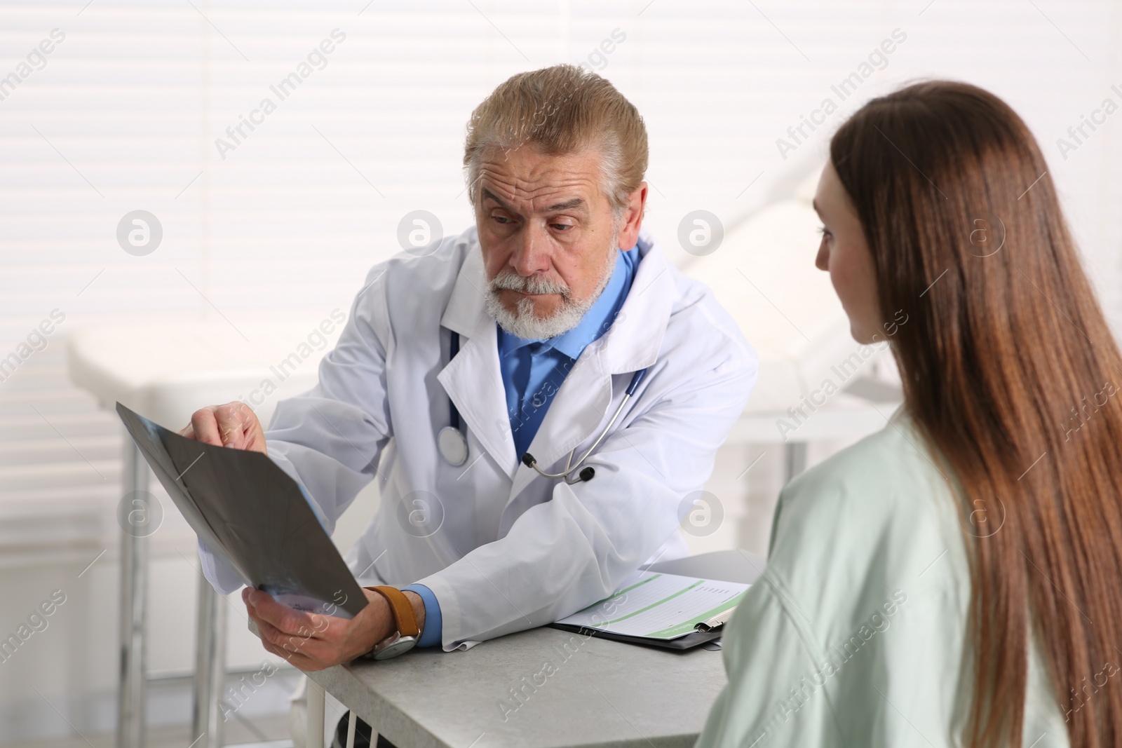 Photo of Orthopedist showing X-ray picture to patient in clinic