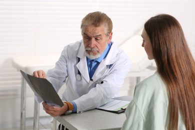 Photo of Orthopedist showing X-ray picture to patient in clinic