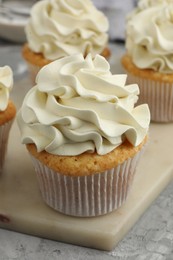 Photo of Tasty cupcakes with vanilla cream on grey table, closeup