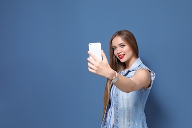 Photo of Attractive young woman taking selfie on color background