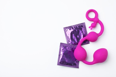 Photo of Anal balls and condoms on white background, top view. Sex game