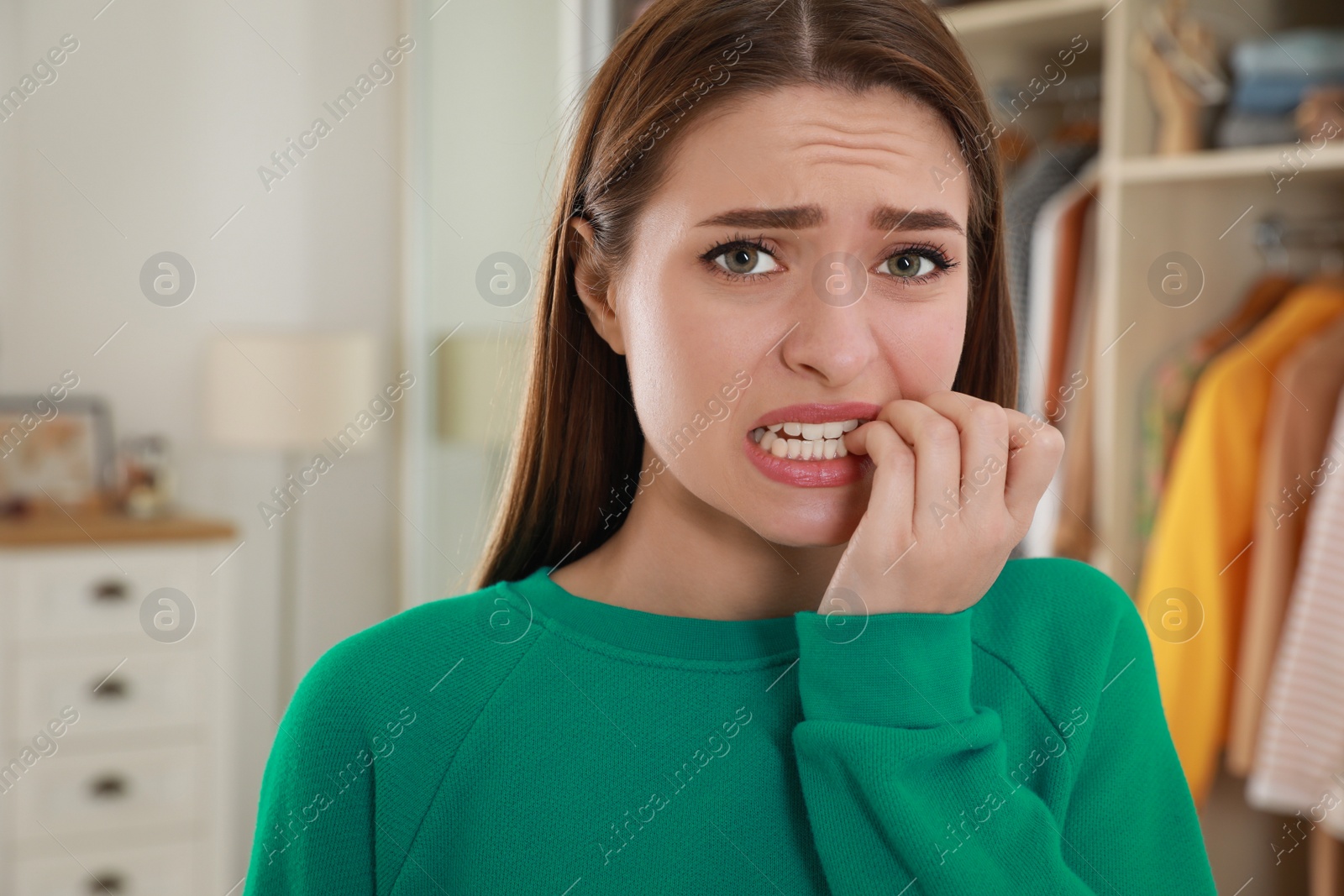 Photo of Young woman biting her nails at home