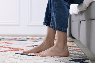 Woman on carpet with pattern at home, closeup. Space for text