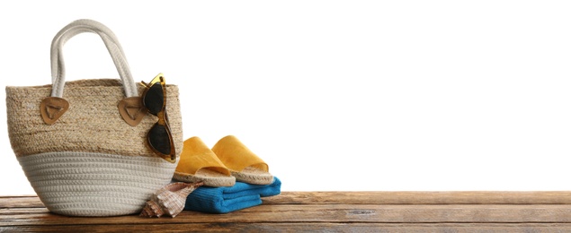 Stylish bag with beach accessories on wooden table. Space for text