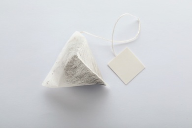 Photo of Unused pyramid tea bag with tag on white background, top view. Space for text