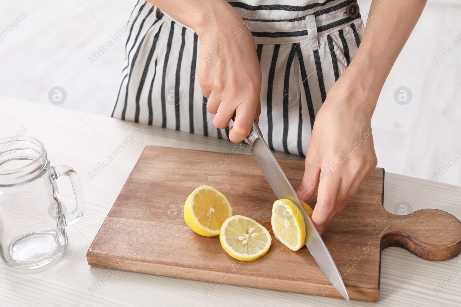 Photo of Young woman preparing lemonade on table, closeup. Natural detox drink