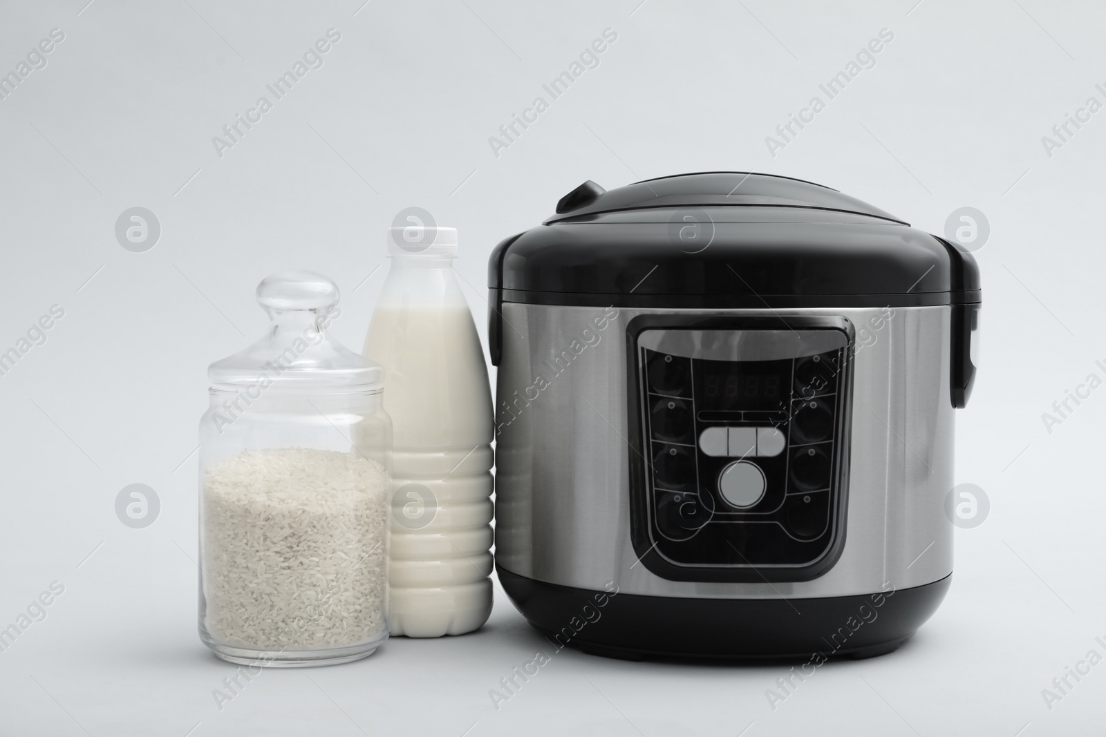 Photo of Modern electric multi cooker, rice and milk on grey background