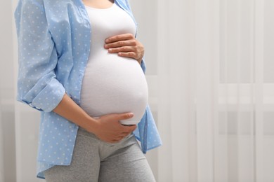 Photo of Pregnant woman indoors, closeup. Space for text