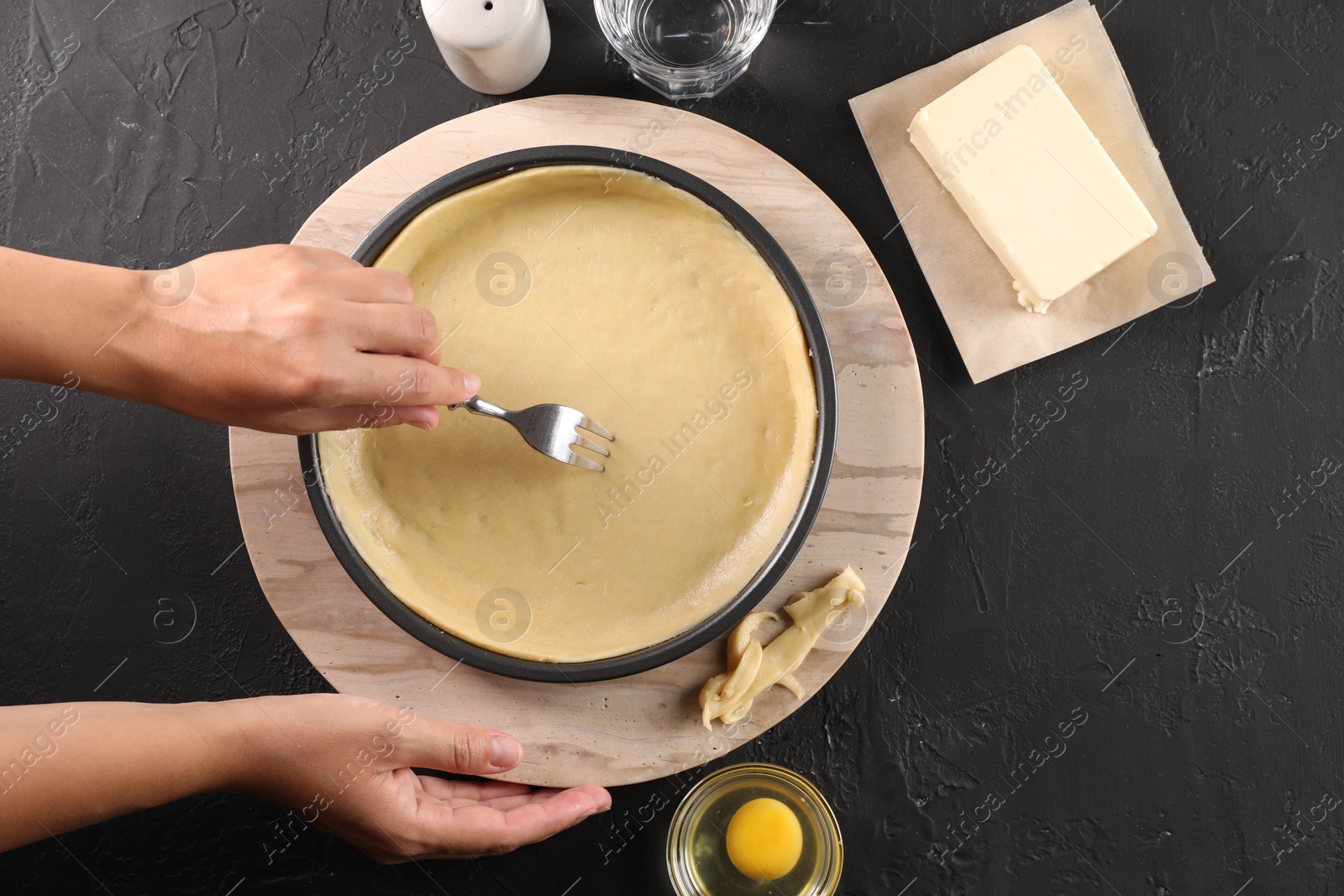 Photo of Woman making quiche at black table, top view