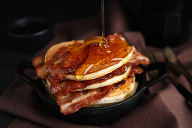 Delicious pancakes with maple syrup and fried bacon on table, closeup