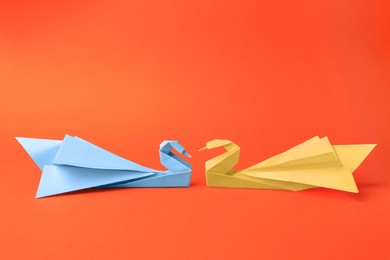 Photo of Origami art. Beautiful paper swans on orange background