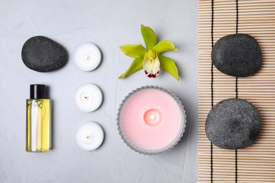 Flat lay composition with spa stones and burning candles on grey table