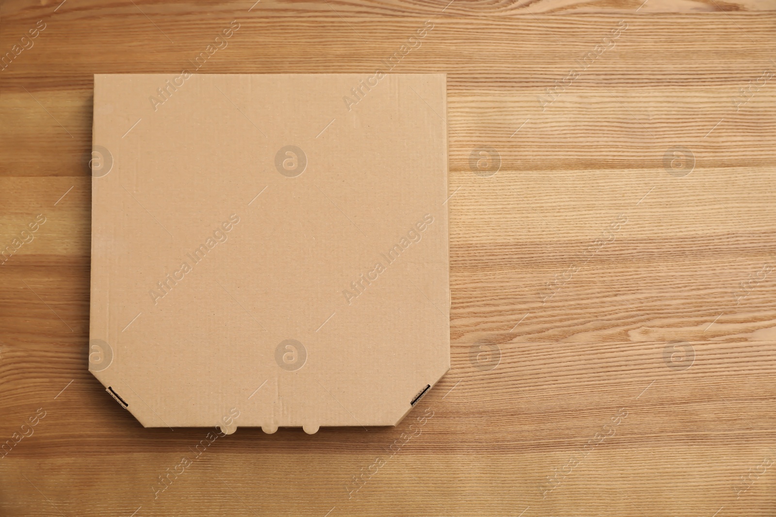 Photo of Cardboard pizza box on wooden background, top view. Mockup for design