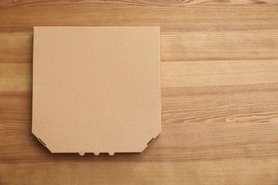 Cardboard pizza box on wooden background, top view. Mockup for design