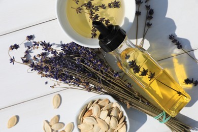 Photo of Healthy cooking oil, lavender flowers and pumpkin seeds on white wooden table, closeup