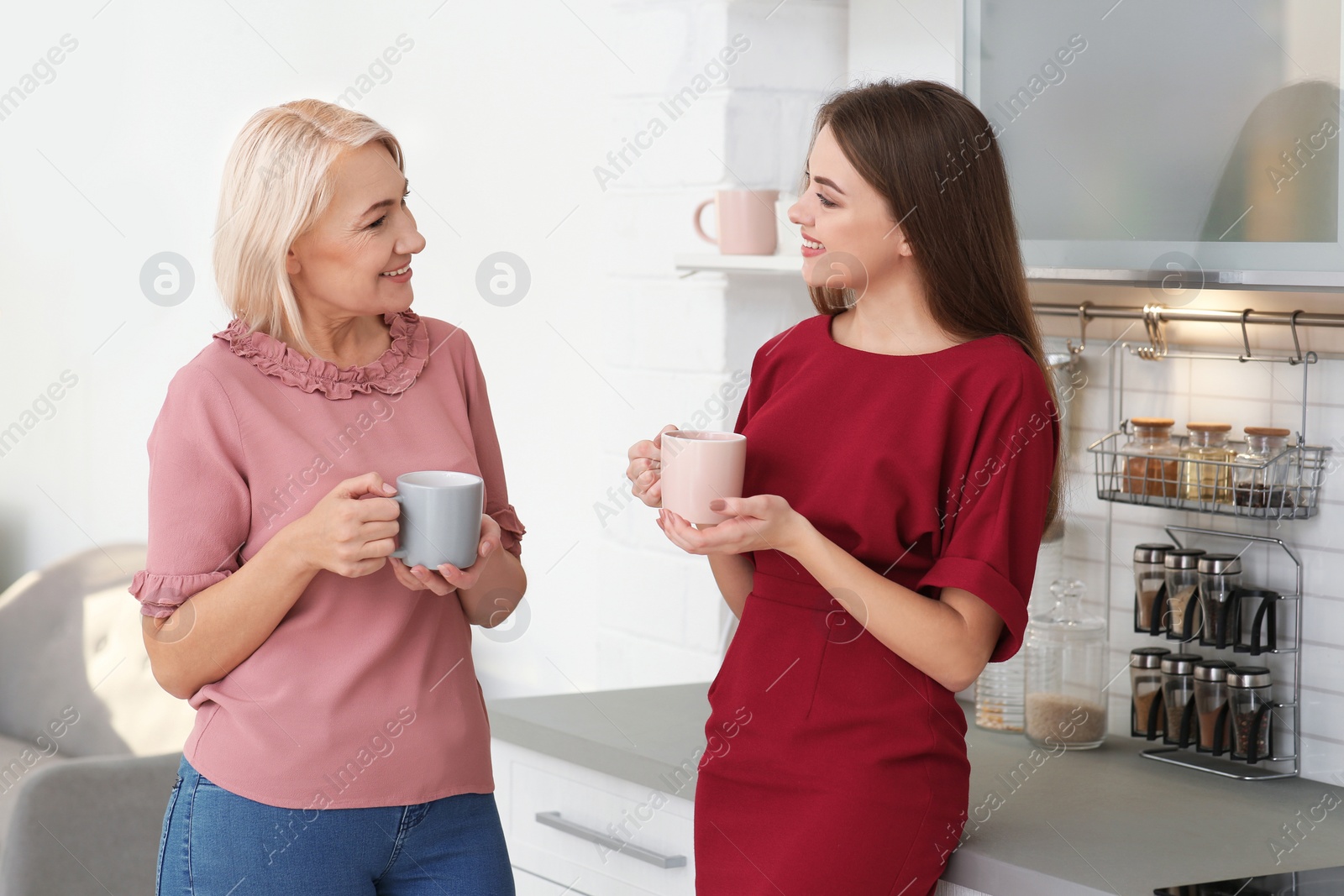 Photo of Portrait of mature woman and her daughter drinking tea in kitchen