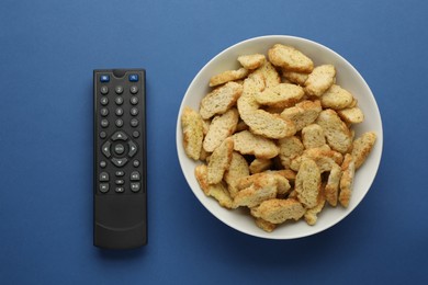 Photo of Remote control and rusks on blue background, flat lay