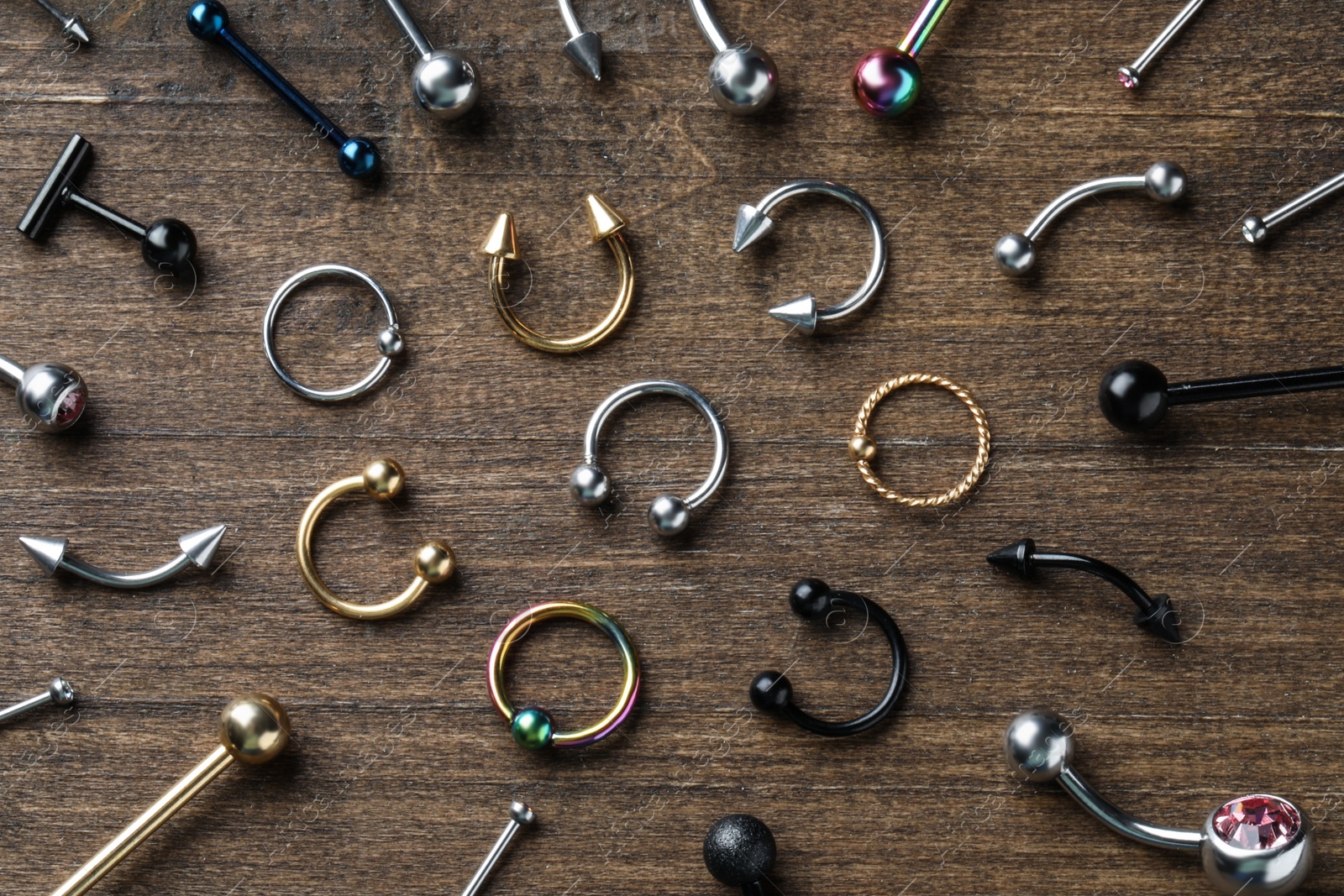 Photo of Stylish piercing jewelry on wooden table, flat lay