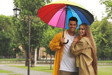 Lovely couple with umbrella walking under rain in park