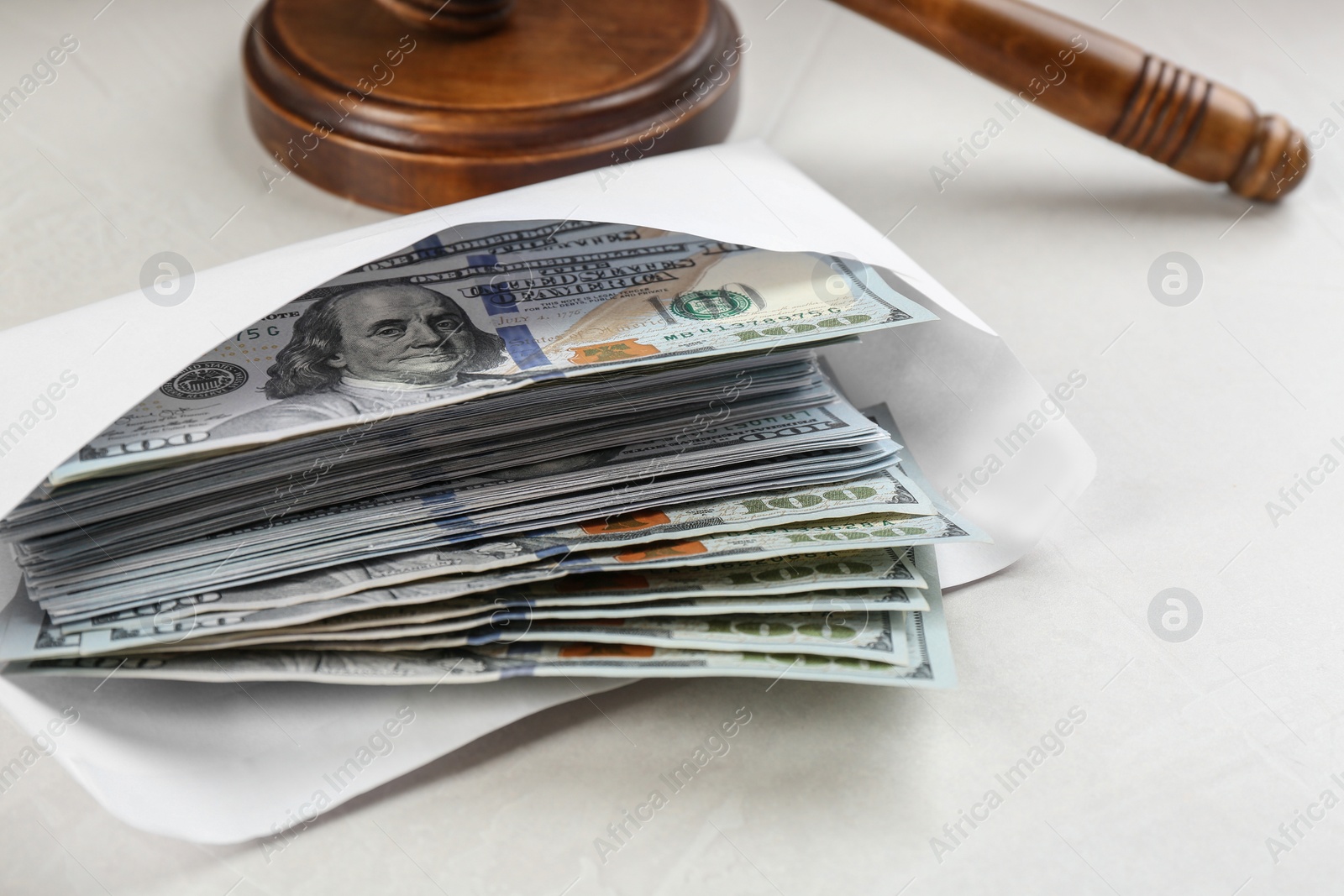 Photo of Dollar bills and gavel on light grey stone table, closeup. Bribe concept