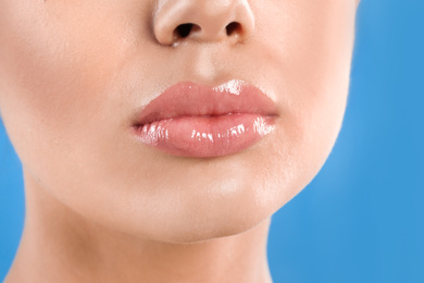 Photo of Young woman with beautiful full lips on light blue background, closeup