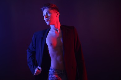 Photo of Sexy young man on dark background in neon lights