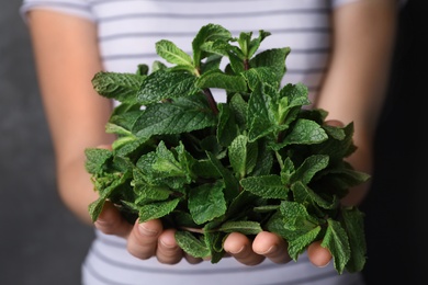 Young woman holding bunch of fresh mint, closeup