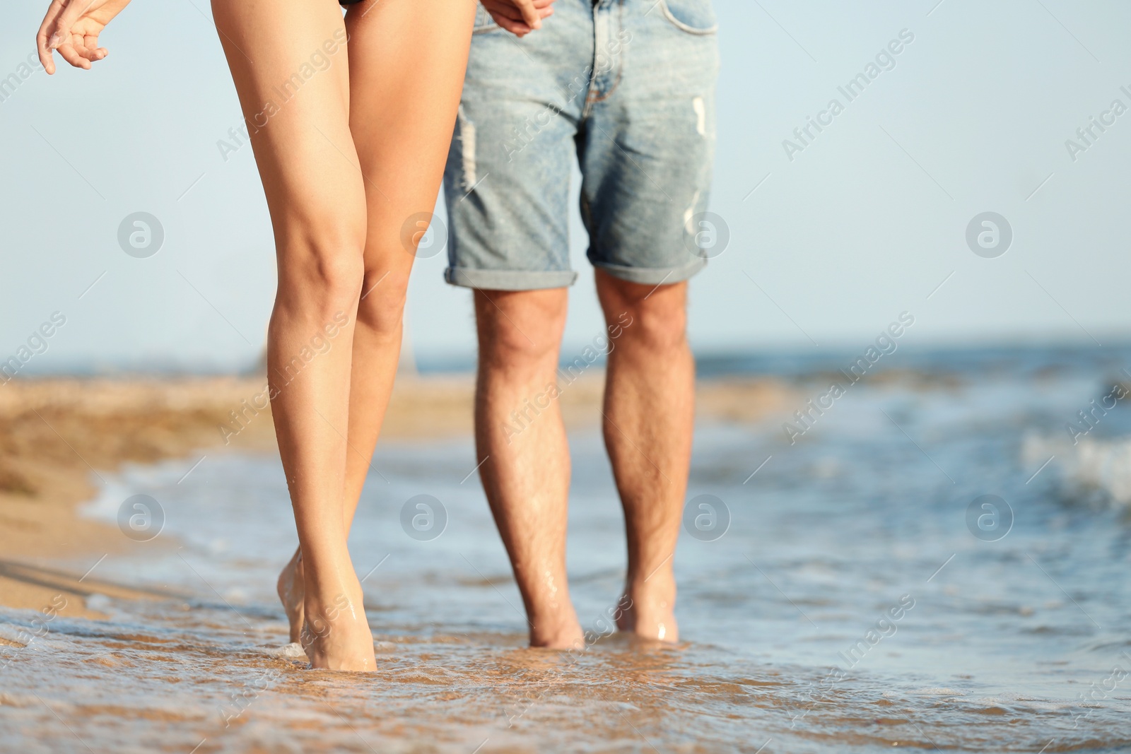 Photo of Young couple spending time together on beach, closeup of legs