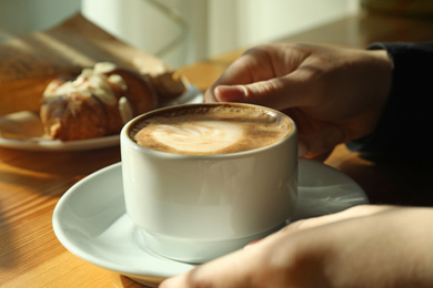 Photo of Woman with cup of fresh aromatic coffee at table in cafe