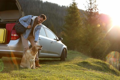 Photo of Happy man and adorable dog near car in mountains. Traveling with pet