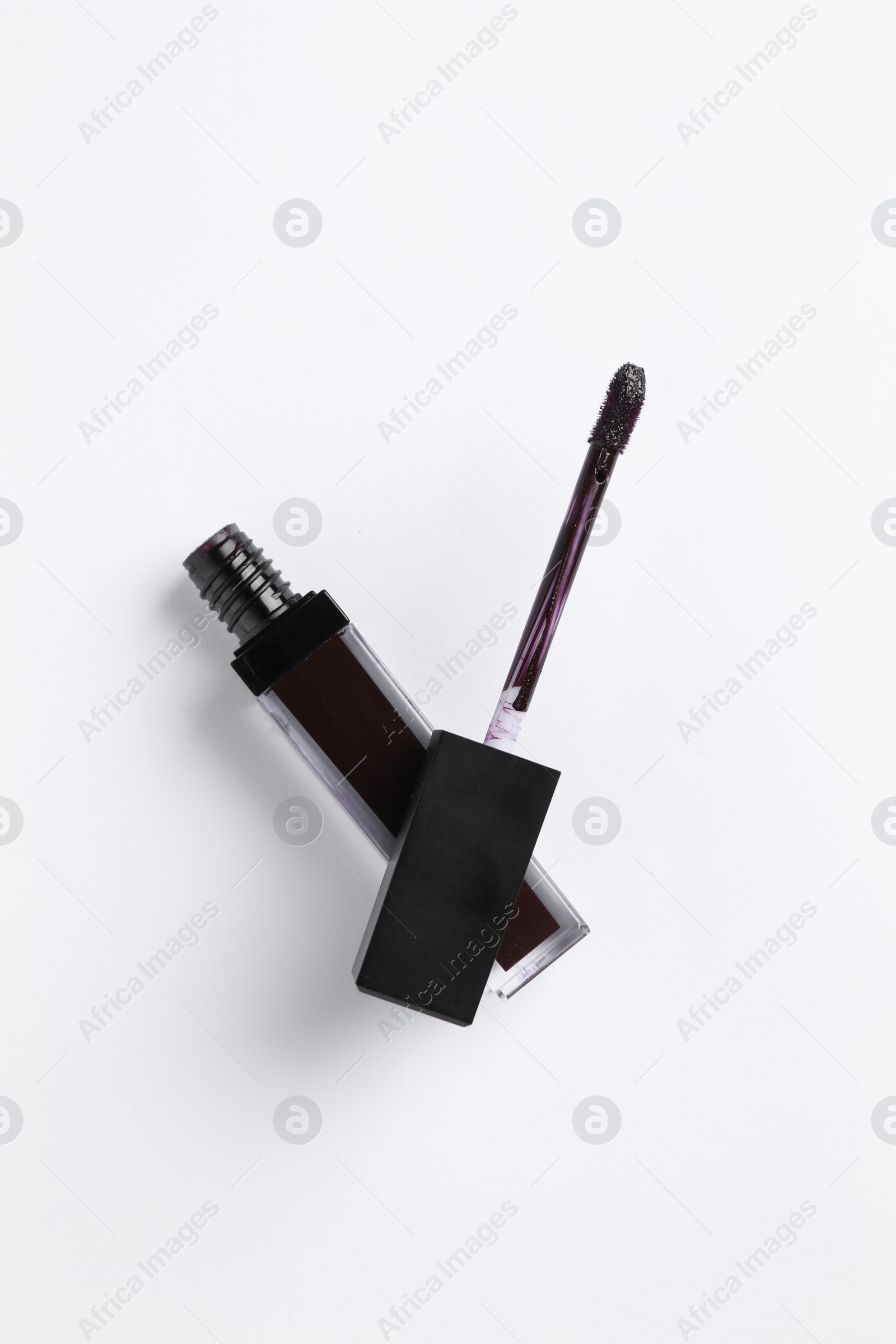 Photo of Purple lip gloss and applicator on white background, top view