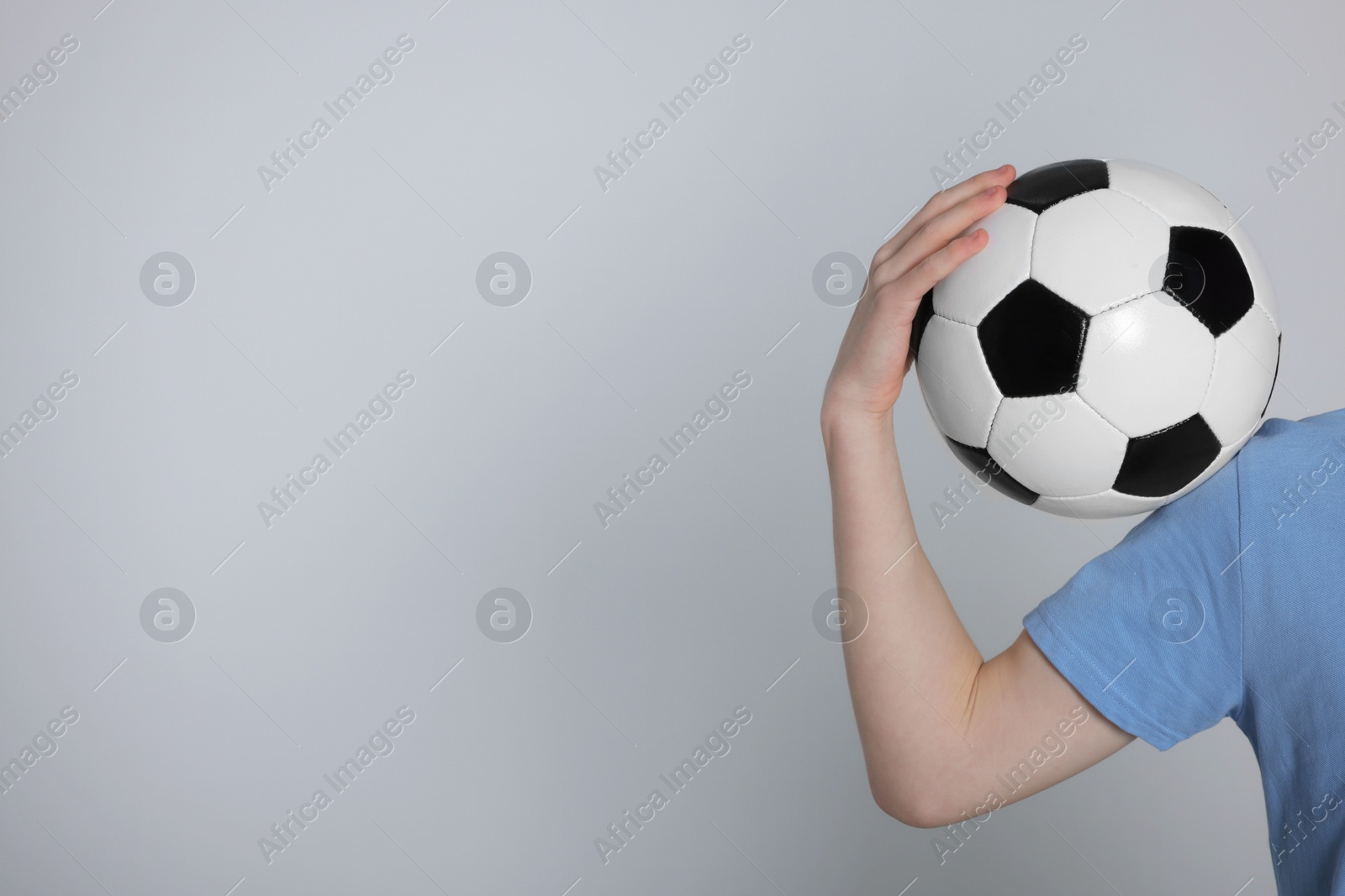 Photo of Boy with soccer ball on light grey background, closeup. Space for text