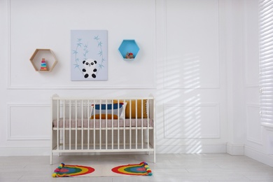 Cute baby room interior with comfortable crib and picture. Space for text