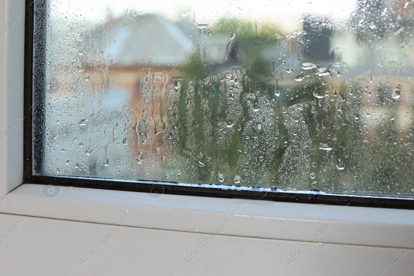 Photo of Wet window on rainy day, closeup. View from inside