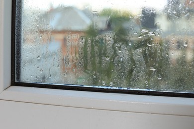 Photo of Wet window on rainy day, closeup. View from inside