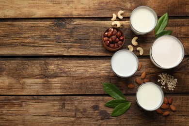 Photo of Different vegan milks and ingredients on wooden table, flat lay. Space for text