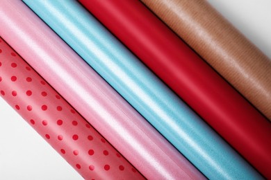 Photo of Rolls of different bright wrapping paper on white background, top view