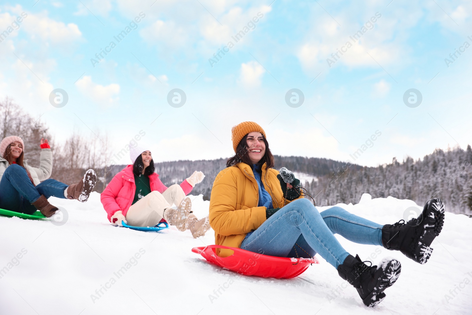 Photo of Group of friends having fun and sledding on snow. Winter vacation