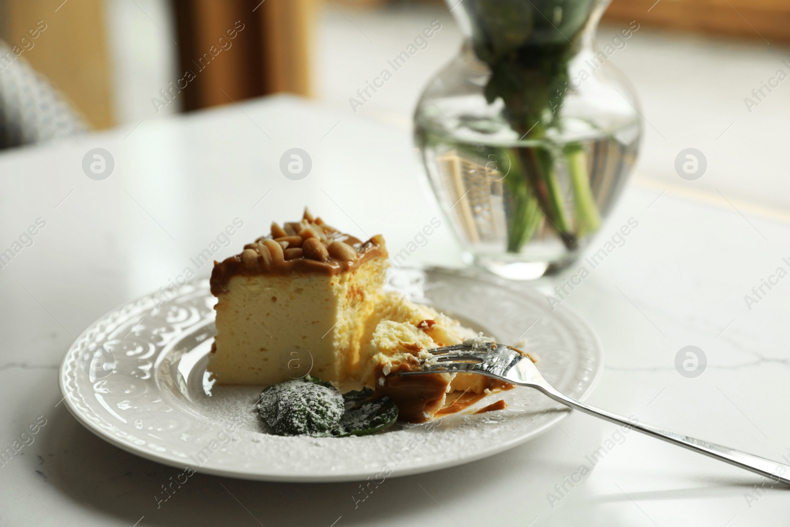 Photo of Tasty dessert and vase with flowers on white table indoors