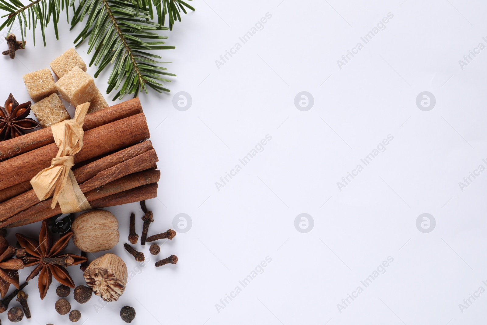 Photo of Different spices, nuts and fir branches on white table, flat lay. Space for text