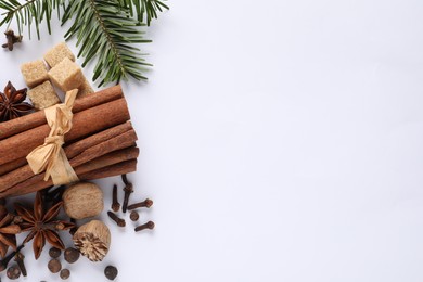 Photo of Different spices, nuts and fir branches on white table, flat lay. Space for text