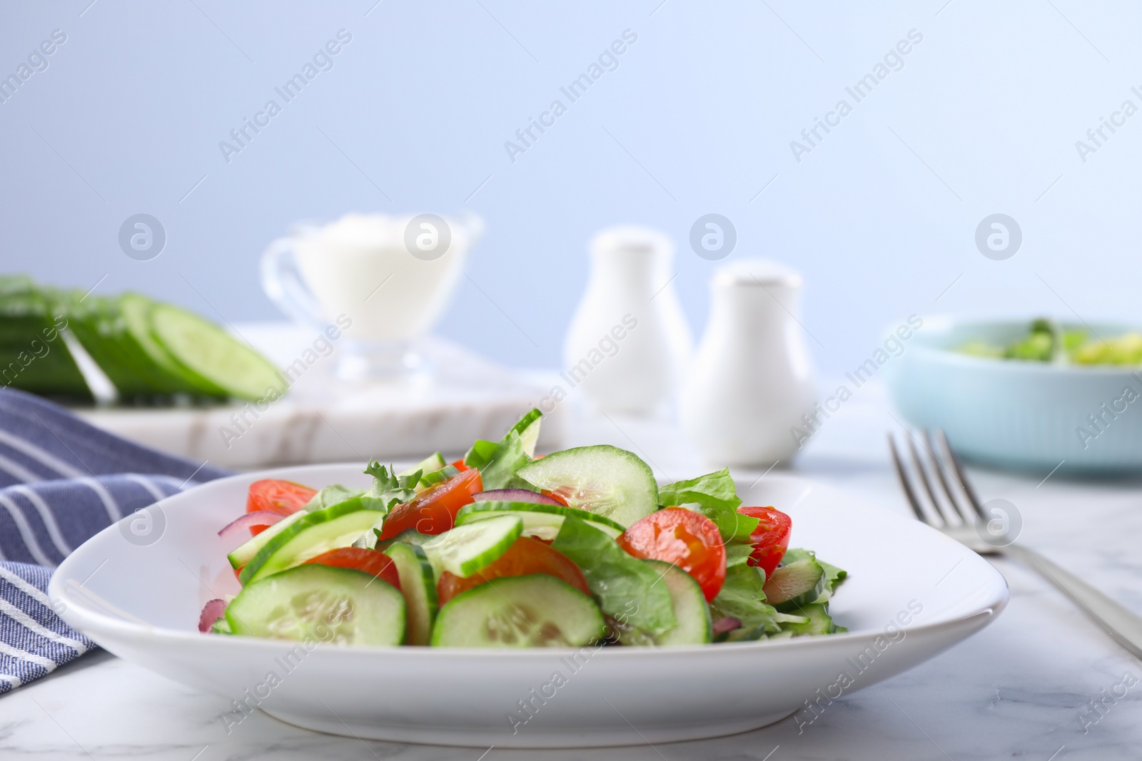 Photo of Plate of vegetarian salad with cucumber, tomato, lettuce and onion served on table