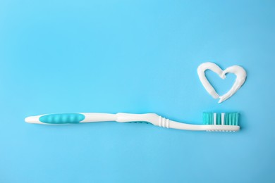 Photo of Heart made with toothpaste and brush on light blue background, top view