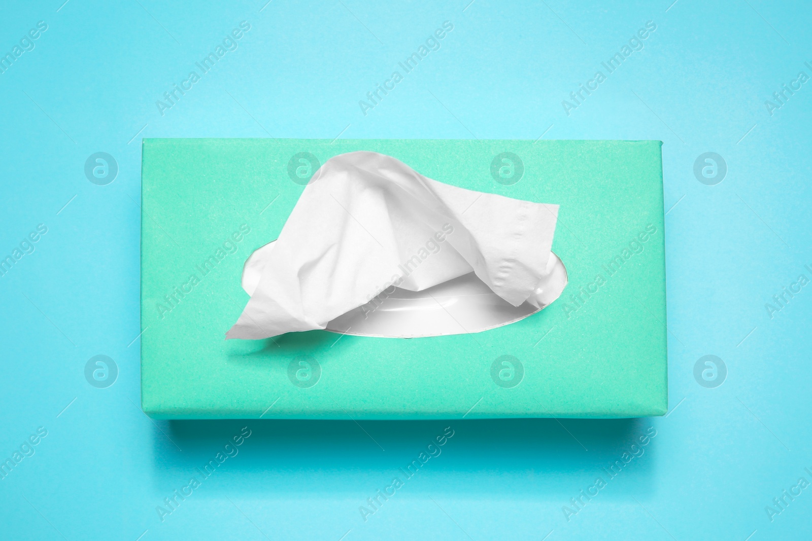 Photo of Box with paper tissues on light blue background, top view