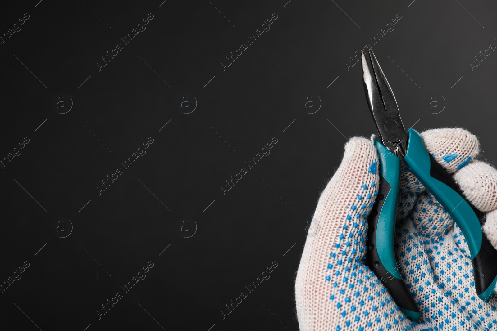 Photo of Man with bent nose pliers on black background, closeup. Space for text